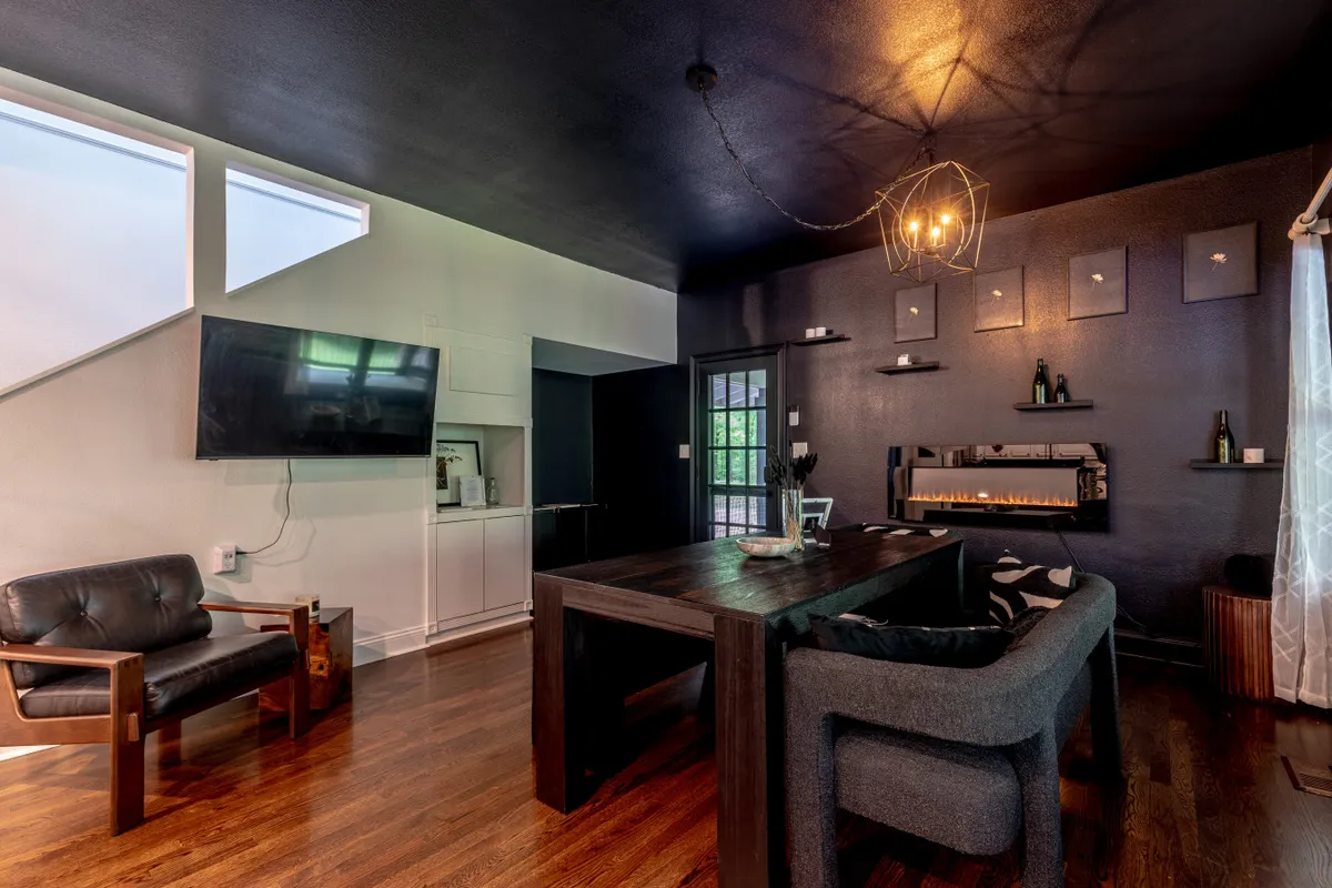 A comfortable and stylish dining area with a dining table under a chandelier, a seating area nearby, and a television. The space is designed for memorable meals, entertaining guests, and cozy movie nights, reflecting the multifaceted use of the open-plan layout.